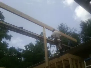Carpenter setting a ridge beam over a new addition frame — Ice Dam Removal by Roofing Brothers in Hanna