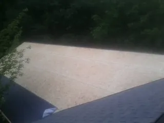 New OSB roof sheathing installed beside an existing shingle roof in Hanna