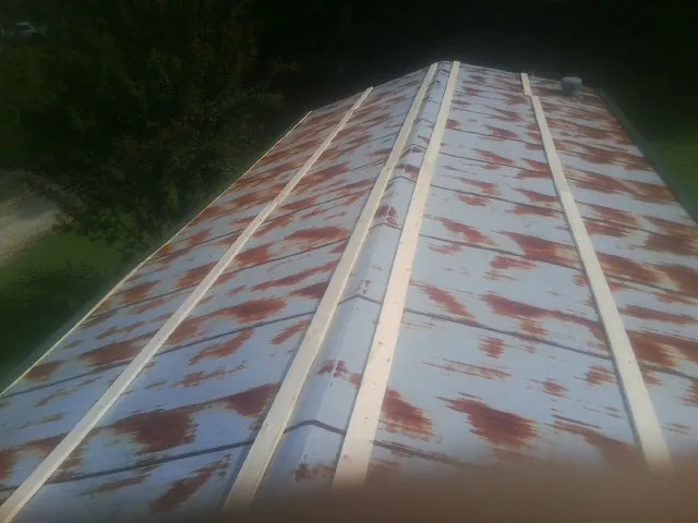Rusted metal roof panels with new wood purlins before replacement — Storm Damage Roof Repair in Hanna by Roofing Brothers