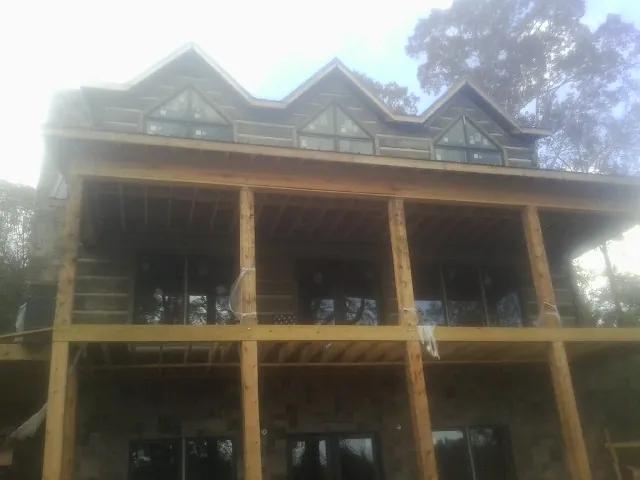 Dormers and porch framing on a large log home under construction — Roof Coating work by our crew in Hanna