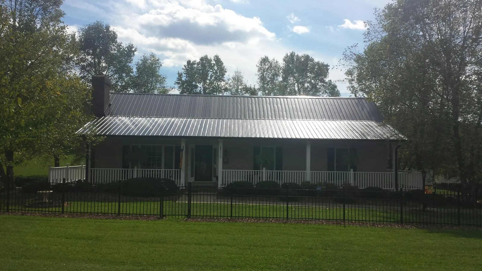 Gray metal roof on a brick ranch with a full width front porch — Gutter Guard Installation work by our crew in Hanna