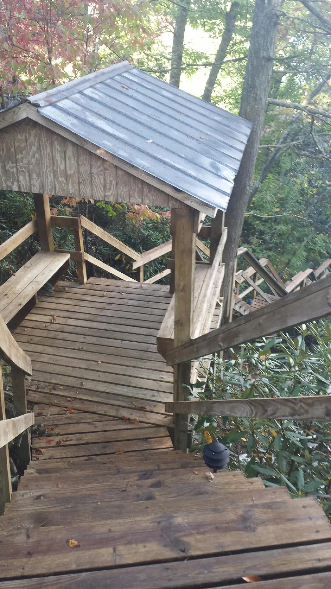 Metal roofed shelter over wooden steps on a wooded walkway — Skylight Repair & Installation work by our crew in Hanna