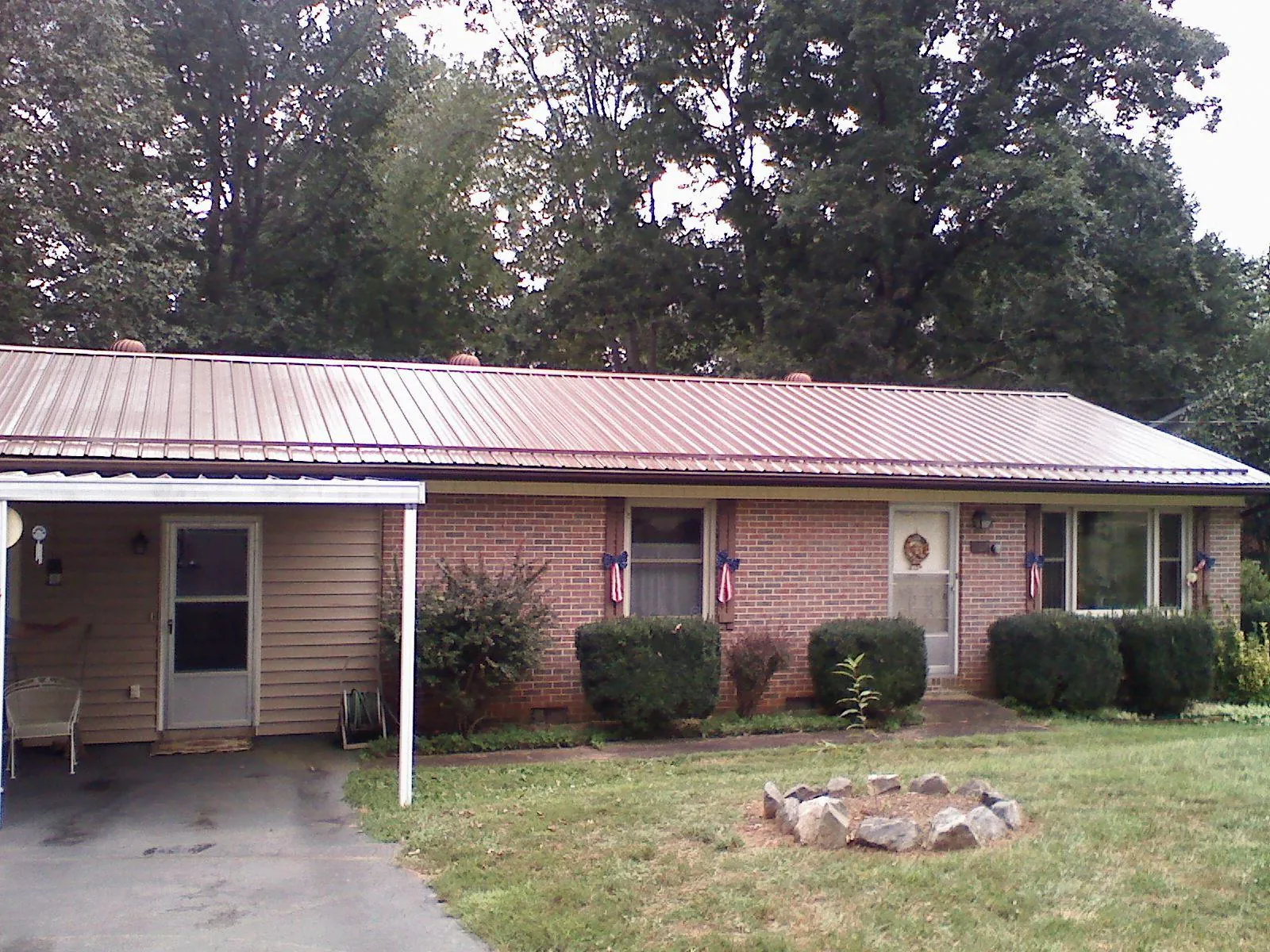 Bronze metal roof and carport on a brick ranch home — Roof Repair work by our crew in Hanna